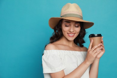 Photo of Beautiful young woman with straw hat and cup of coffee on light blue background. Space for text