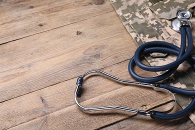 Photo of Stethoscope and military uniform on wooden table, space for text