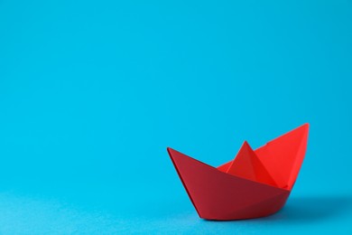 Handmade red paper boat on light blue background. Space for text