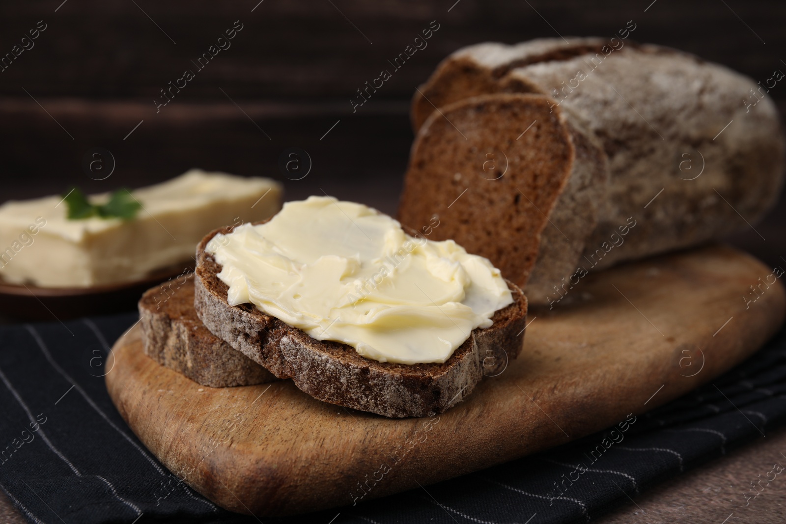 Photo of Slices of tasty bread with butter on grey textured table, closeup
