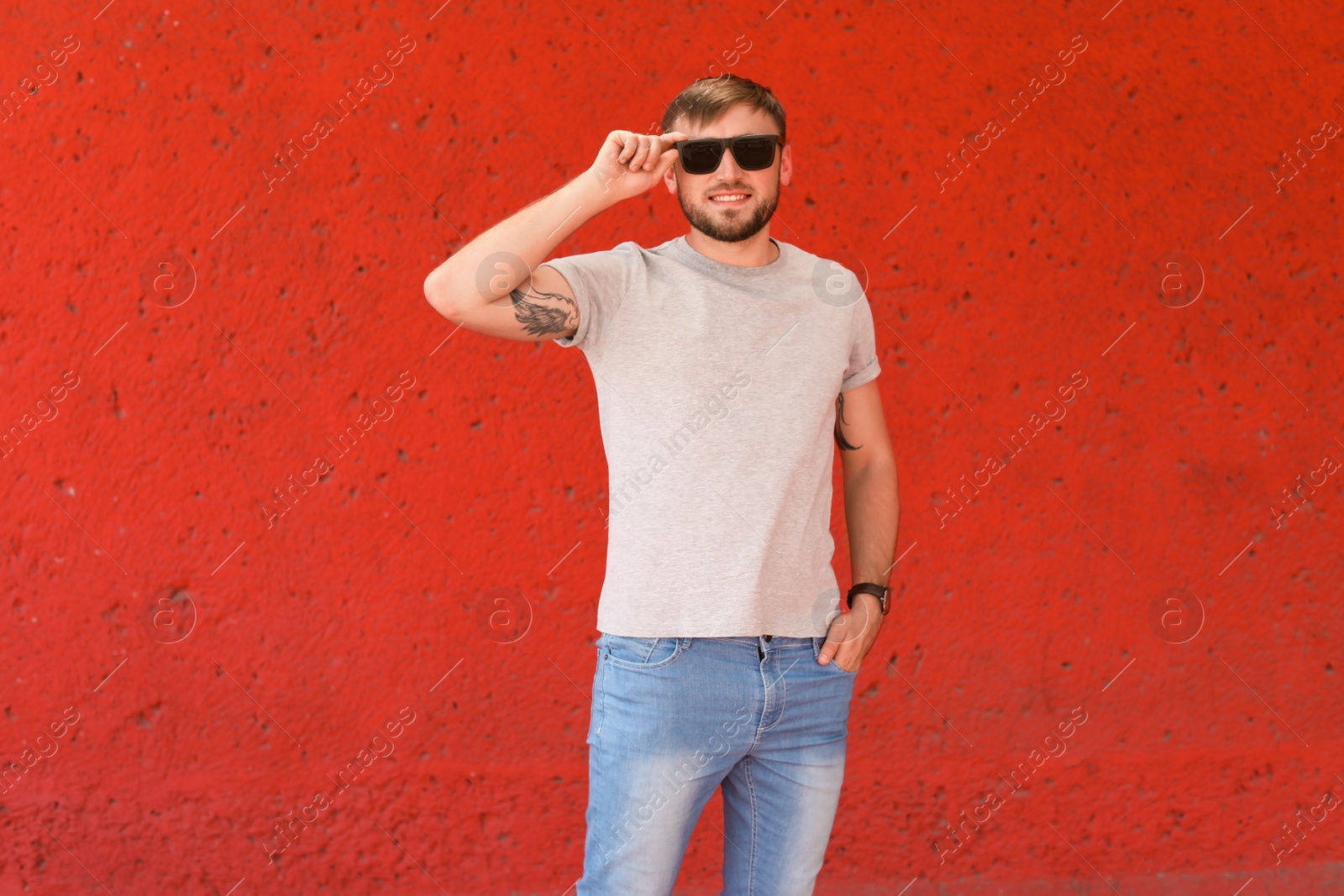 Photo of Young man wearing gray t-shirt near color wall on street