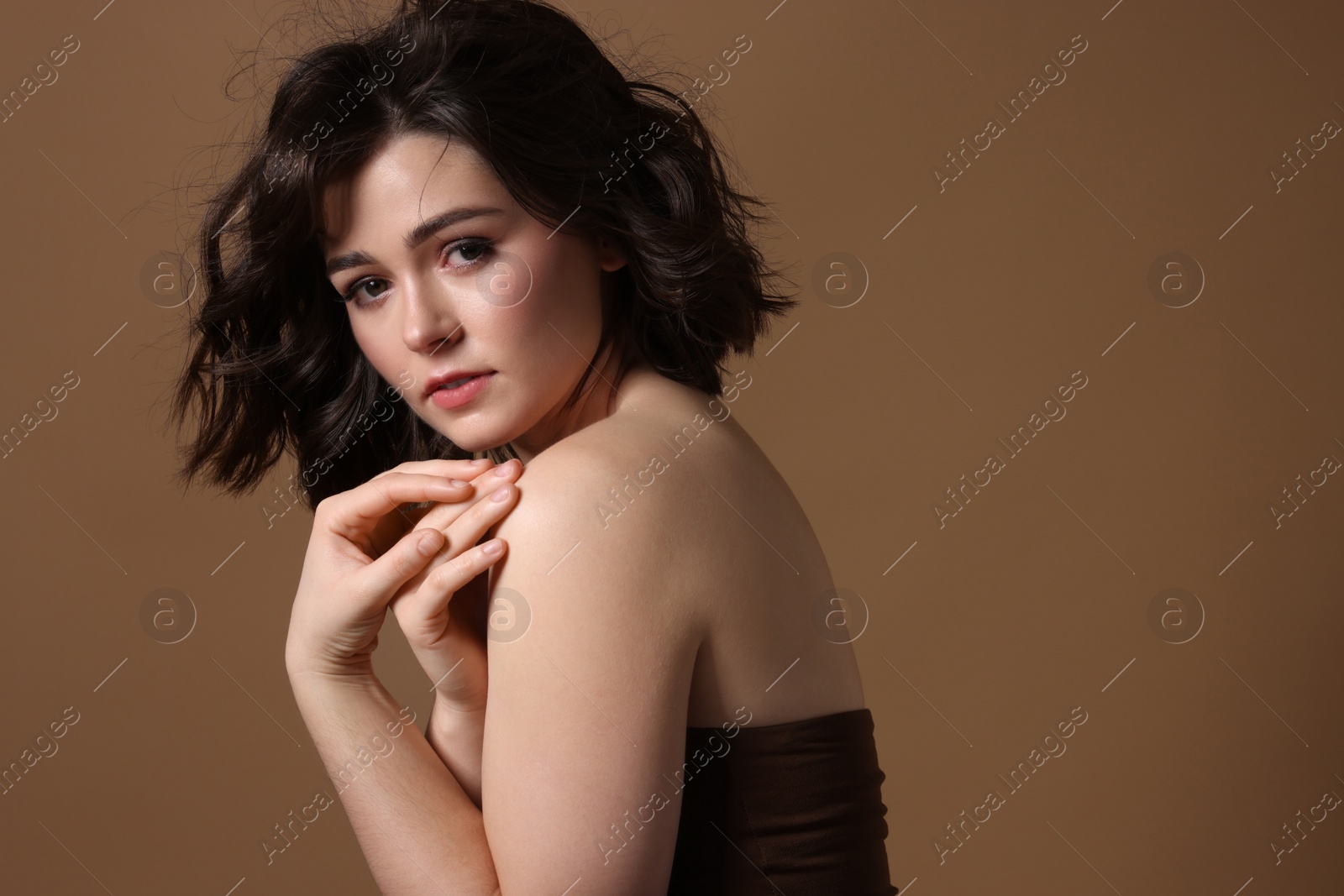 Photo of Portrait of beautiful young woman with wavy hairstyle on brown background. Space for text