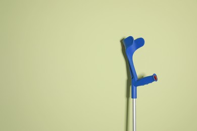 Photo of Elbow crutch on light green background. Space for text