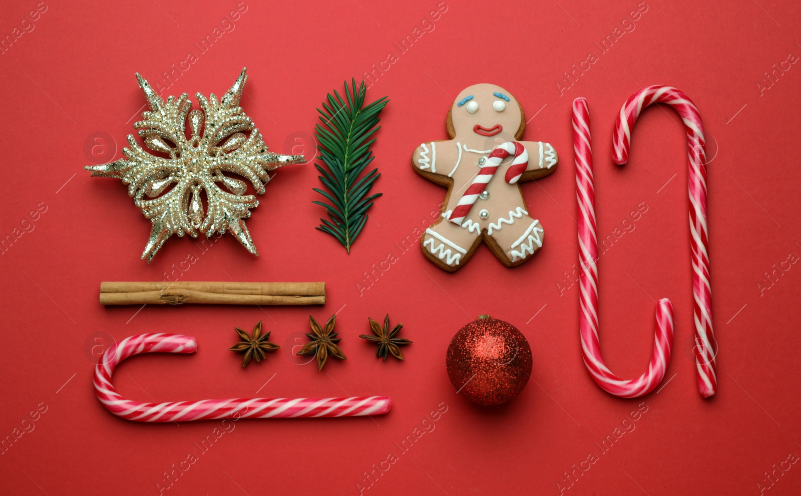 Photo of Flat lay composition with sweet candy canes and Christmas decor on red background