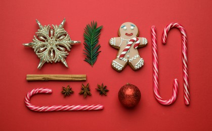 Flat lay composition with sweet candy canes and Christmas decor on red background