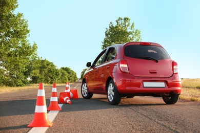 Photo of Red car near fallen traffic cones outdoors. Failed driving school exam