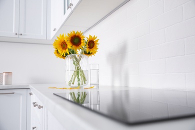 Bouquet of beautiful sunflowers on counter in kitchen. Space for text