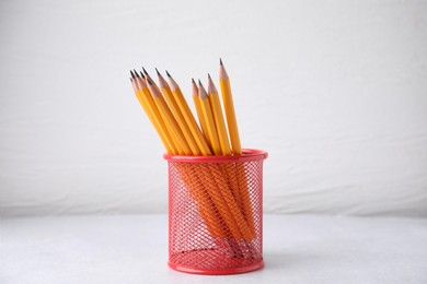 Photo of Many sharp pencils in holder on white background