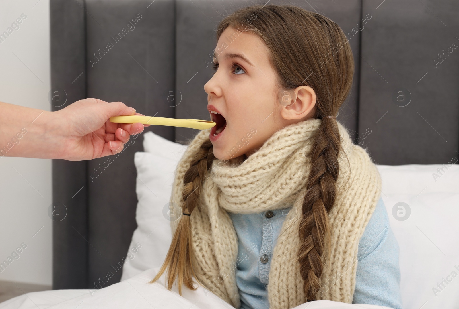 Photo of Mother giving cough syrup to her daughter at home