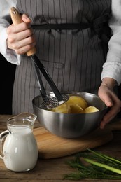 Photo of Woman making mashed potato at wooden table, closeup