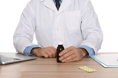 Photo of Professional pharmacist with syrup and laptop at table against white background, closeup