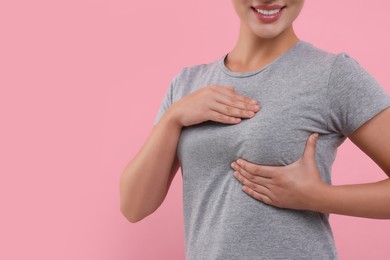 Photo of Woman doing breast self-examination on pink background, closeup. Space for text