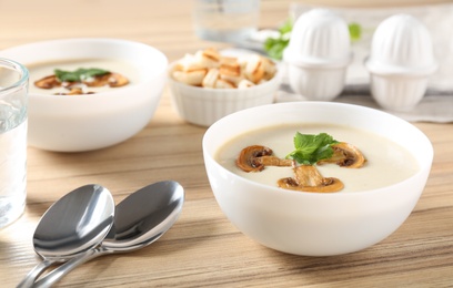 Photo of Delicious cream soup with mushrooms on wooden table