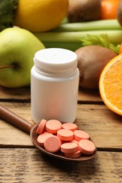 Photo of Dietary supplements. Bottle, pills in spoon and food products on wooden table