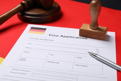 Immigration to Germany. Visa application form, gavel, stamp and pen on flag, closeup