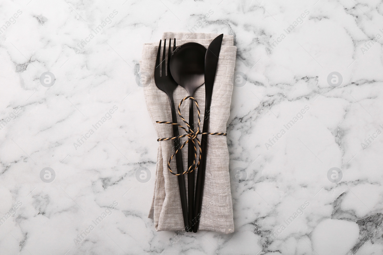 Photo of Set of stylish cutlery and napkin on white marble table, top view