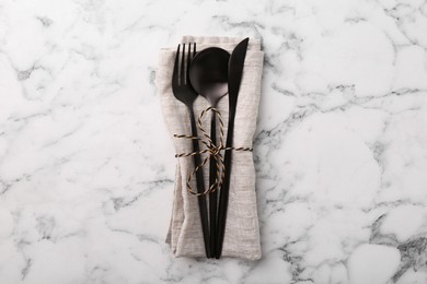 Photo of Set of stylish cutlery and napkin on white marble table, top view