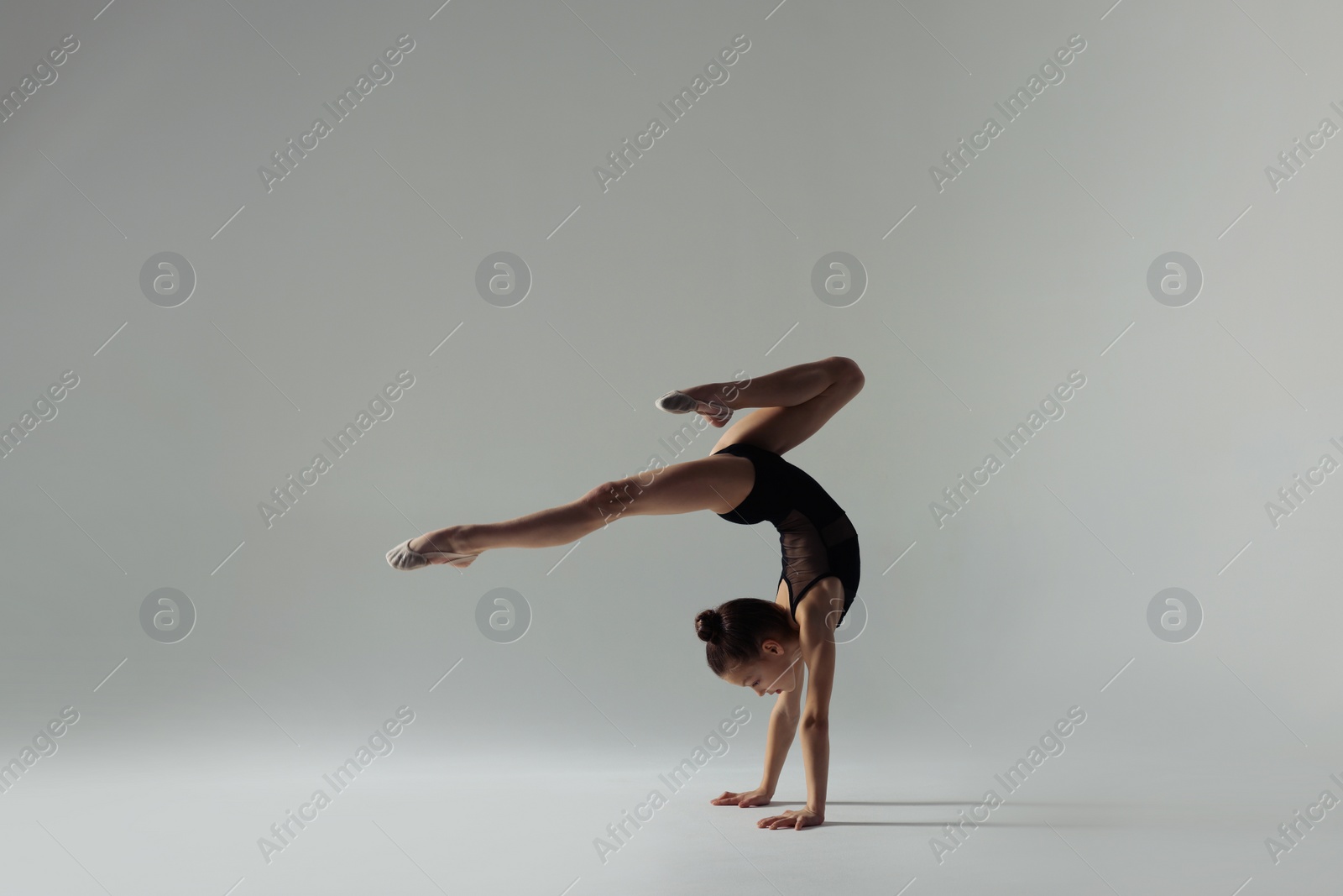 Photo of Cute little gymnast doing handstand on white background