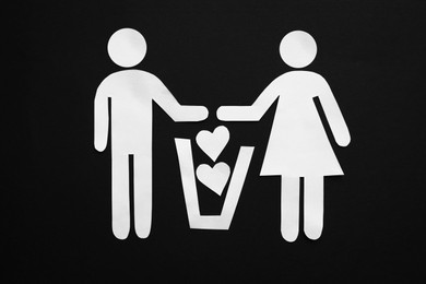 Photo of Divorce concept. Paper cutoutscouple, trash can and hearts on black background, flat lay