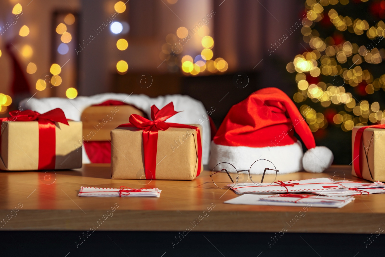 Photo of Santa's Claus workplace. Gift boxes, letters on table and costume in room with Christmas tree