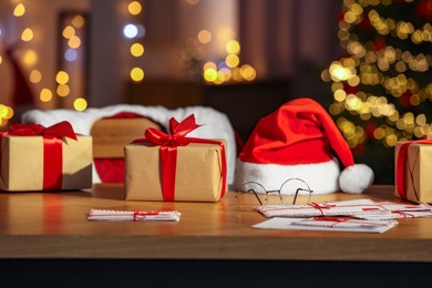 Photo of Santa's Claus workplace. Gift boxes, letters on table and costume in room with Christmas tree