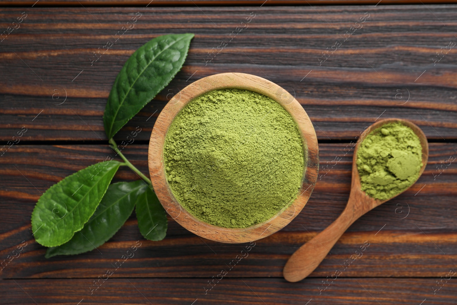 Photo of Bowl and spoon with green matcha powder on wooden table, flat lay