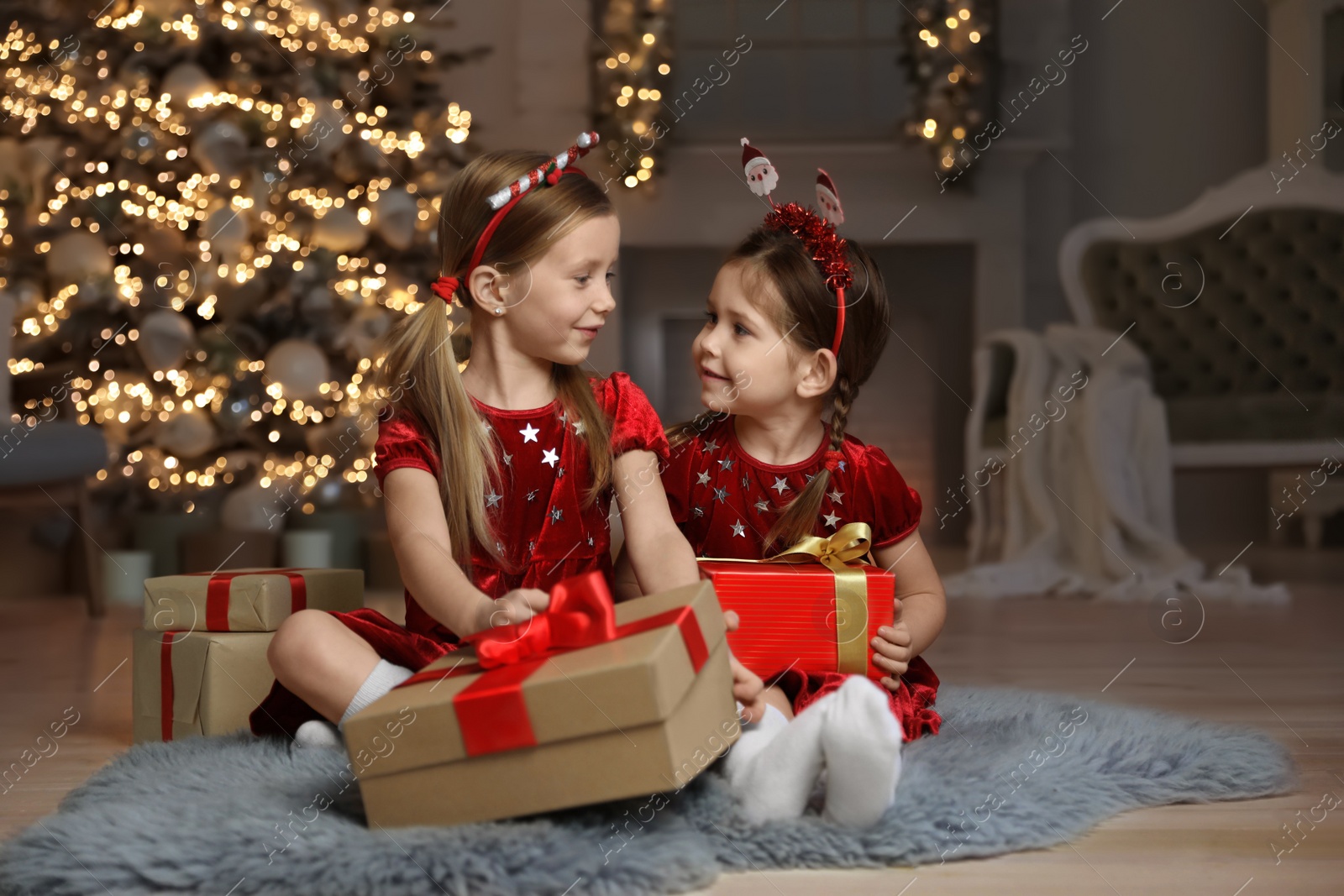 Photo of Cute little children with Christmas gifts in living room