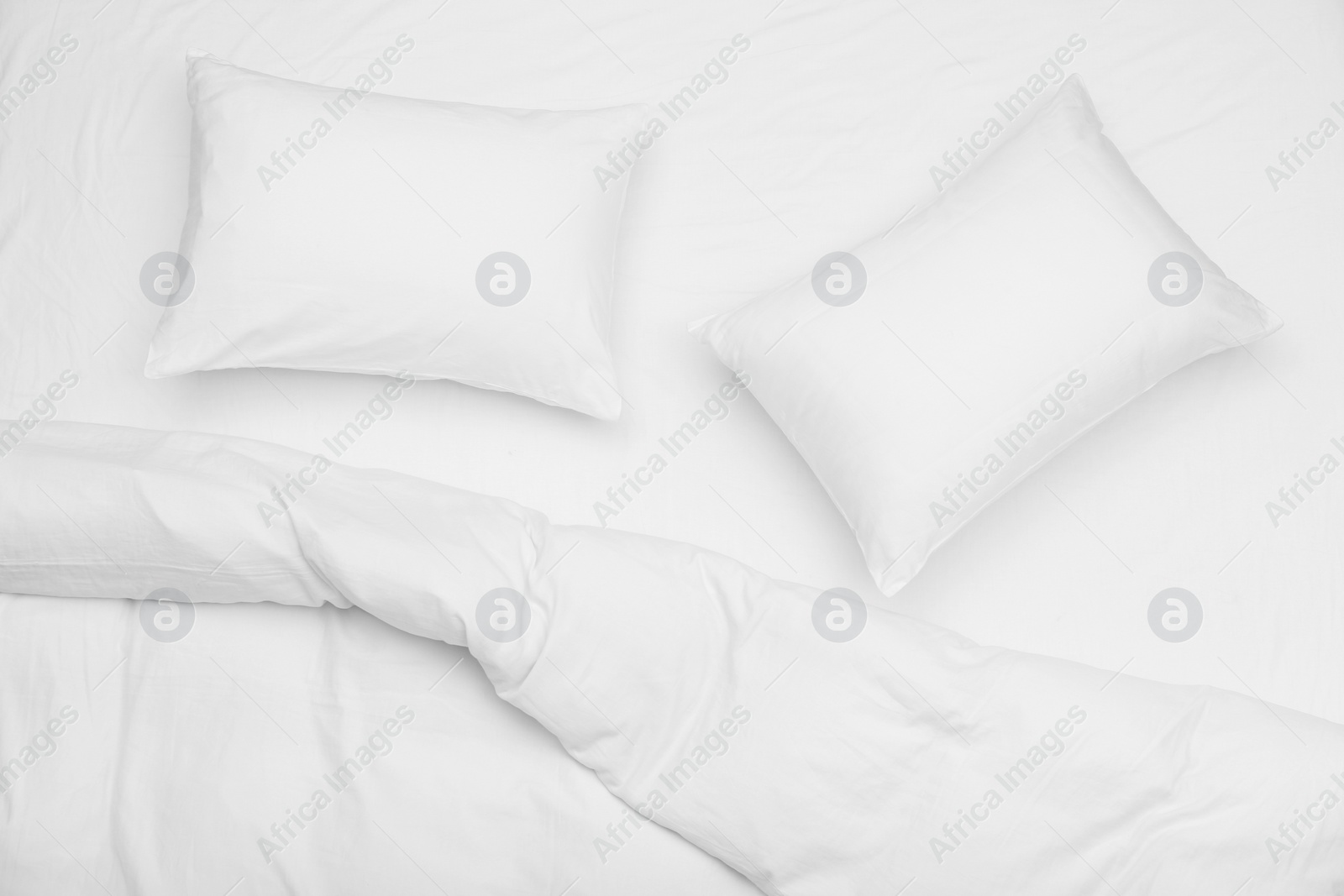 Photo of Soft white pillows and blanket on bed, top view