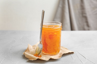 Photo of Jar and spoon with sweet jam on table