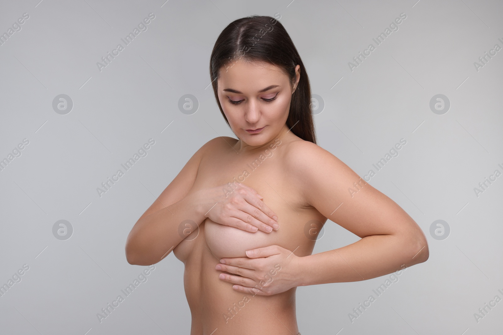 Photo of Mammology. Naked woman doing breast self-examination on light grey background