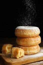 Delicious donuts with powdered sugar on wooden table