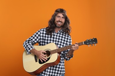 Photo of Hippie man playing guitar on orange background