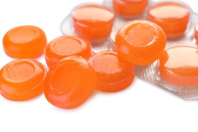 Photo of Many orange cough drops on white background