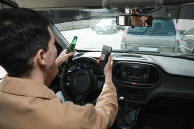 Photo of Man with bottle of beer and smartphone in car. Don't drink and drive concept
