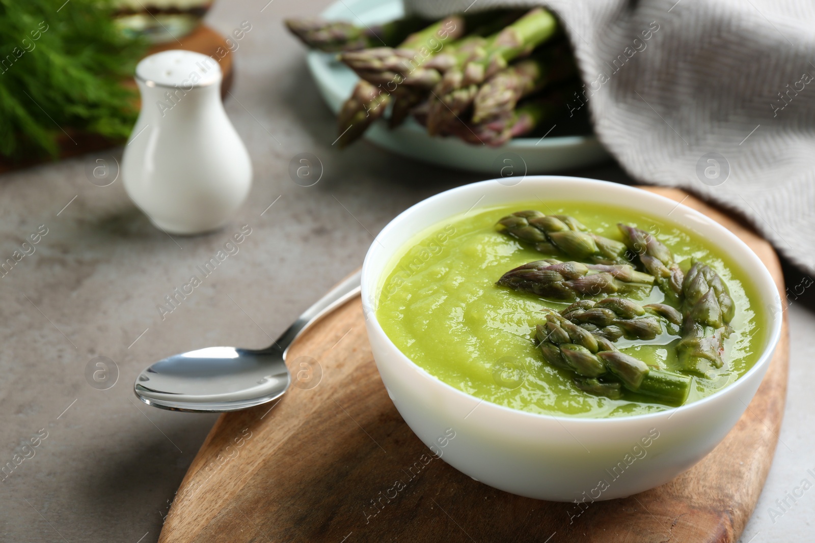 Photo of Delicious asparagus soup served on grey table