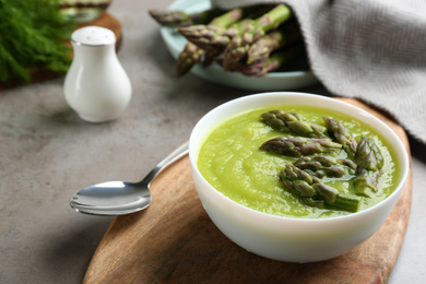 Photo of Delicious asparagus soup served on grey table