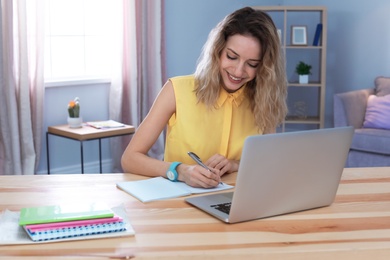 Young woman working with laptop at desk. Home office