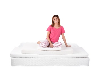 Woman sitting on mattress pile against white background