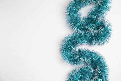 Light blue tinsel on white background, top view. Space for text