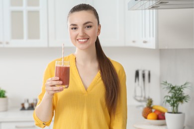 Photo of Beautiful young woman with delicious smoothie in kitchen