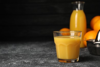 Photo of Tasty fresh oranges and juice on black table, closeup. Space for text