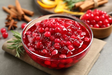 Photo of Fresh cranberry sauce served in glass bowl on grey table