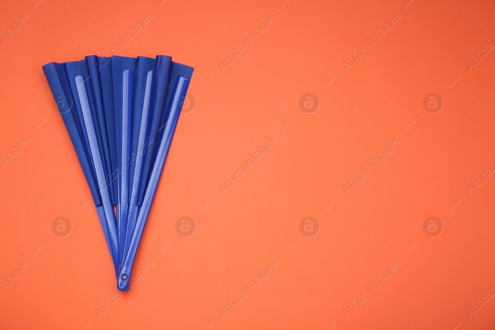 Photo of Bright blue hand fan on orange background, top view. Space for text