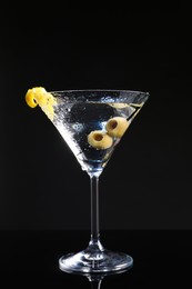 Photo of Martini cocktail with olives and lemon twist on dark background