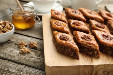 Photo of Delicious sweet baklava with walnuts on wooden table, closeup. Space for text