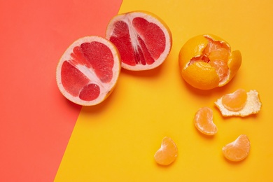 Photo of Delicious fresh cut grapefruit and tangerine on color background, above view
