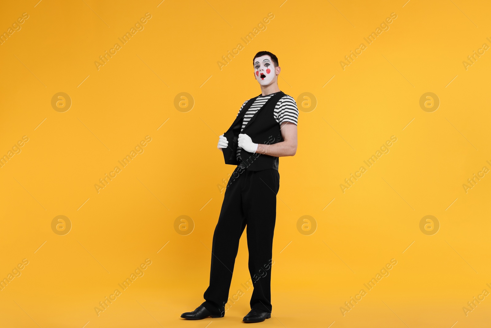 Photo of Mime artist making shocked face on orange background