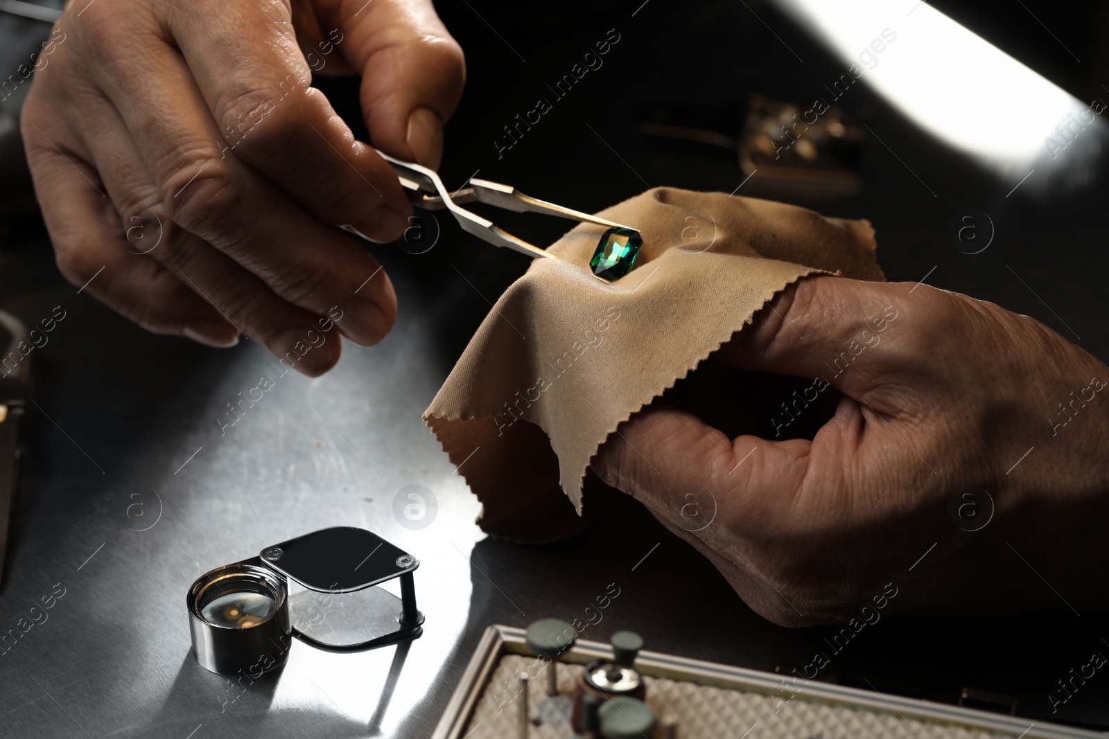 Photo of Professional jeweler working with gemstone at table, closeup