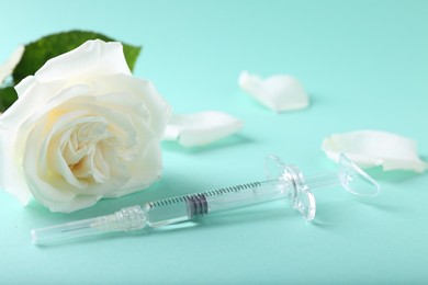 Photo of Cosmetology. Medical syringe and rose flower on turquoise background, closeup