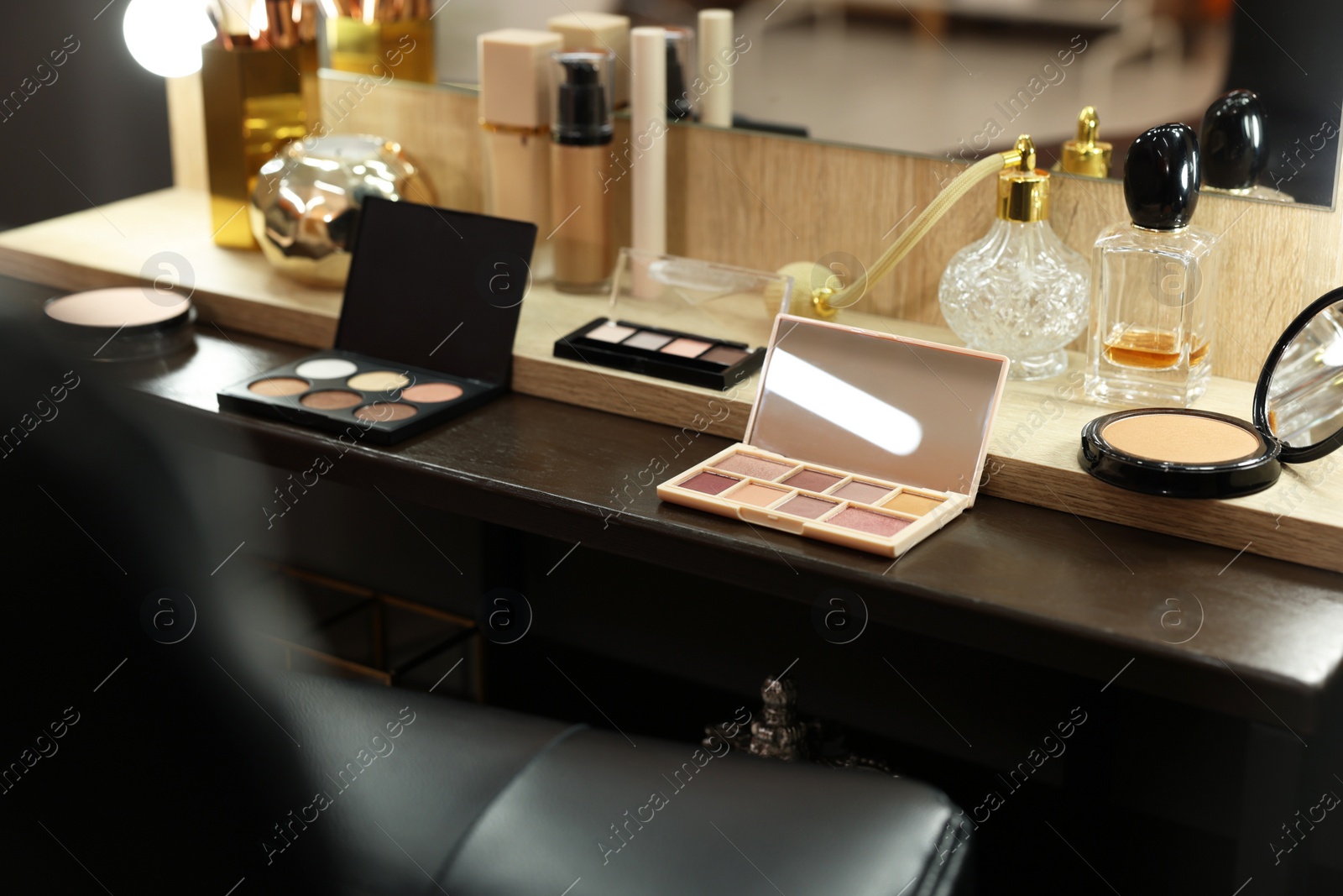 Photo of Makeup room. Cosmetic products and perfumes on wooden dressing table indoors